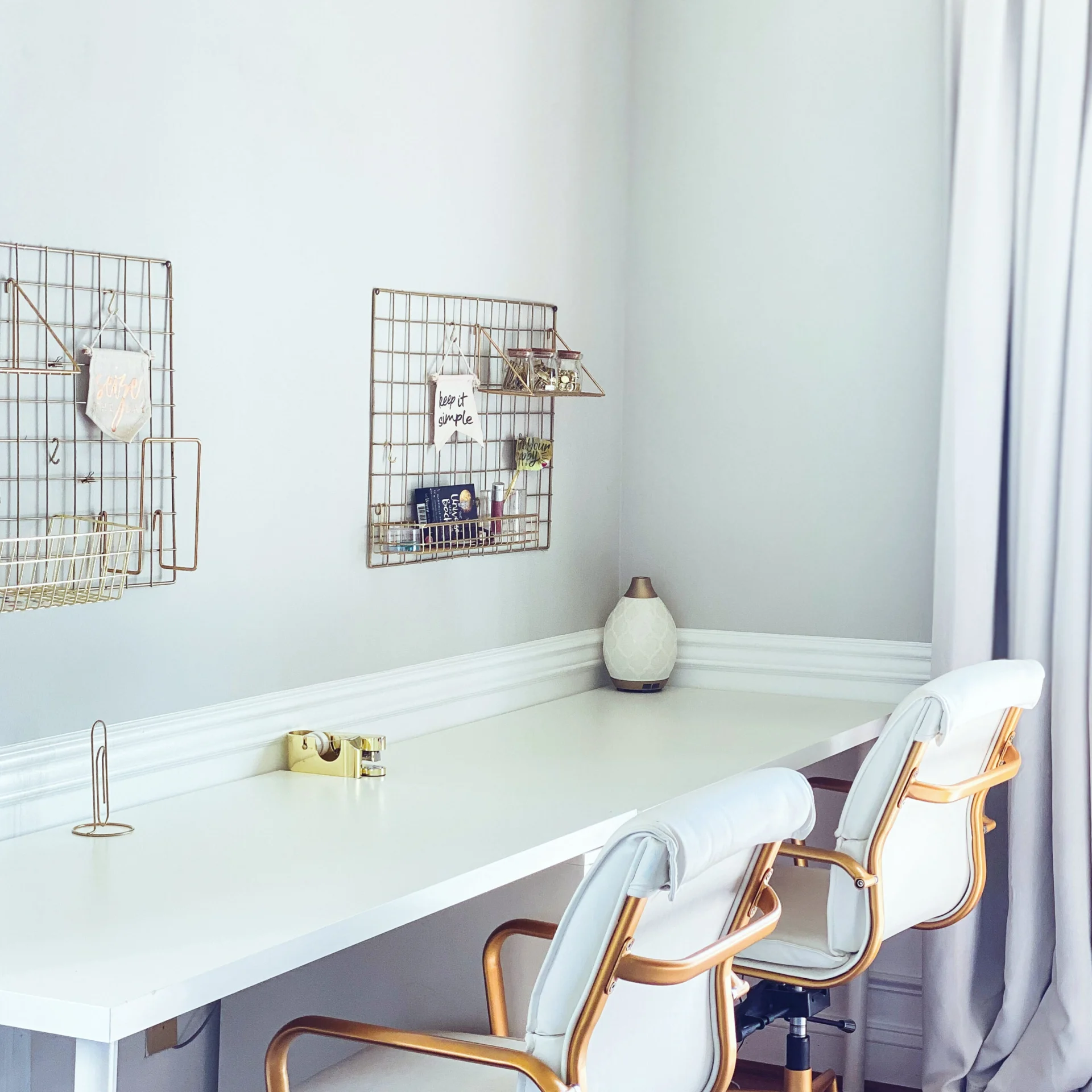 A clean and minimalist home office desk with gold accents and a white upholstered chair.