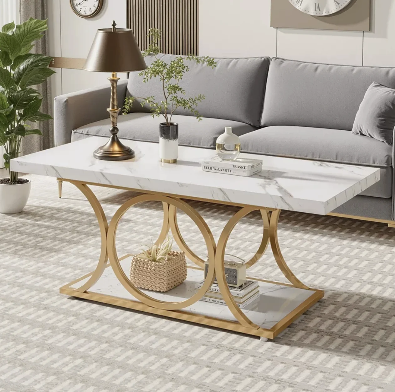 A rectangular white marble coffee table with gold geometric legs, placed in a living room setting.