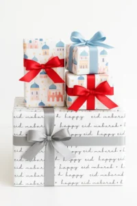 Stack of Eid Mubarak gift boxes with decorative mosque and star patterns, tied with red, blue, and silver ribbons.